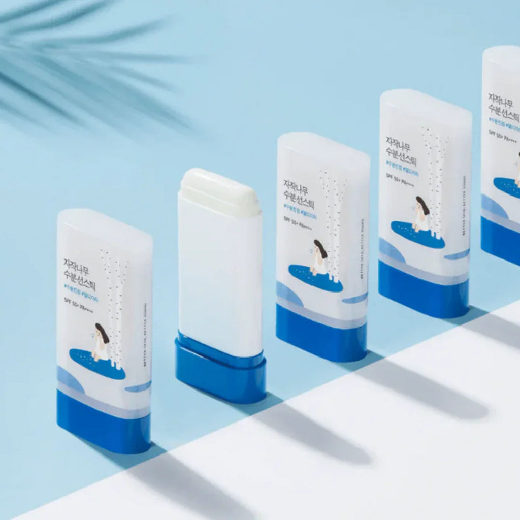 Multiple sticks of Birch Moisturizing Sun Stick SPF 50 PA++++ with blue and white packaging on light blue background