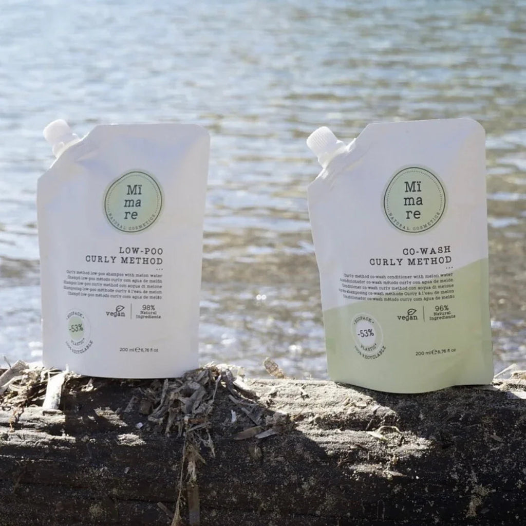 Mimare Low-Poo and Co-Wash Curly Method vegan hair care pouches on a log by water